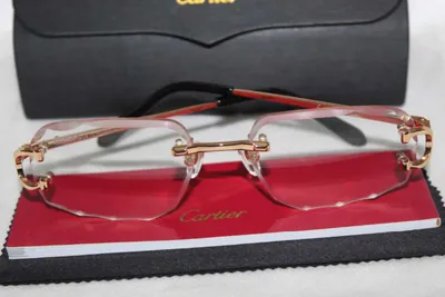 Armazón Cartier al aire con puente y patillas doradas sobre su estuche