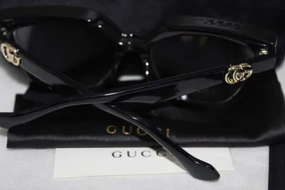 Patillas negras de unos lentes Gucci con la doble G dorada