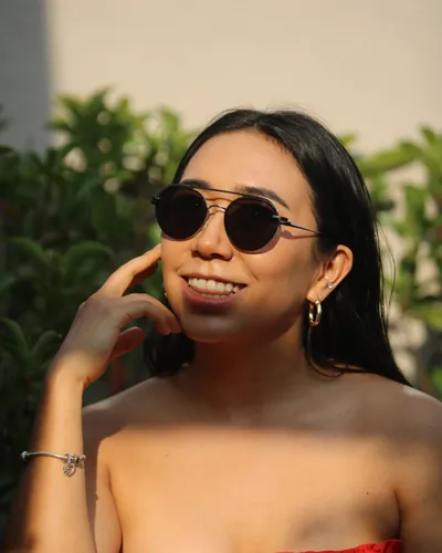 Mujer sonriendo con lentes de sol redondos oscuros