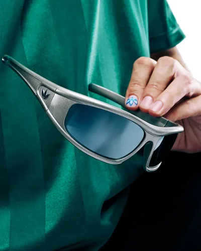 Mano sosteniendo lentes de sol adidas Originals plateados