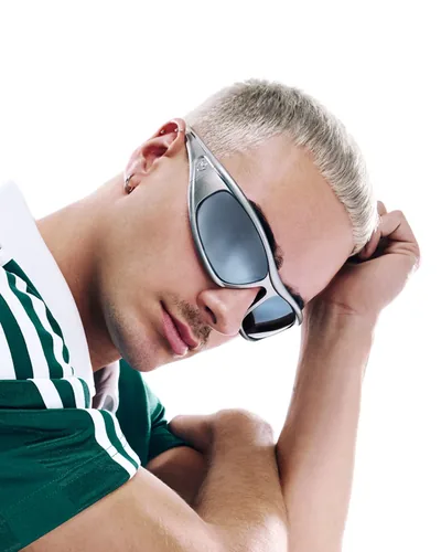 Hombre con lentes de sol adidas Originals plateados y chamarra verde