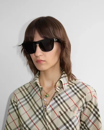 Mujer con lentes de sol Burberry negros y camisa de cuadros
