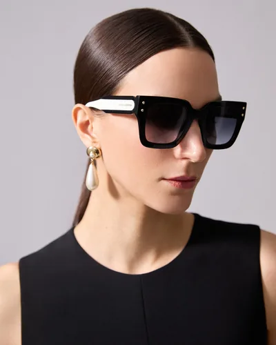 Mujer con lentes de sol Carolina Herrera negros con patillas blancas