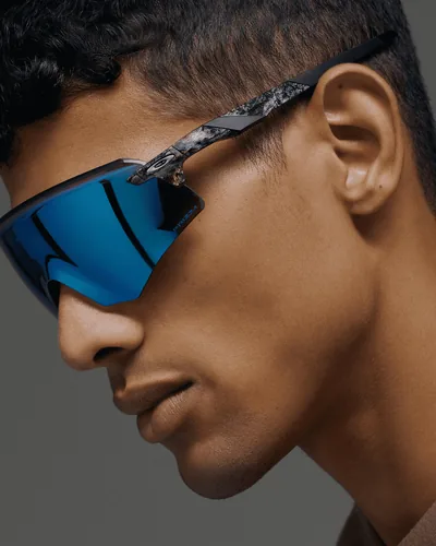 Hombre de perfil con lentes deportivos Oakley de mica azul espejeada