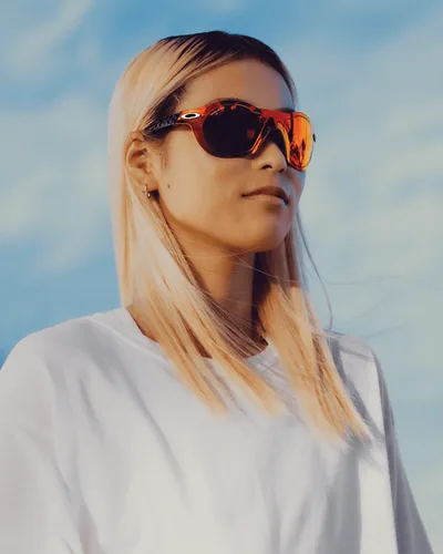 Mujer al aire libre con lentes de sol Oakley de mica naranja espejeada