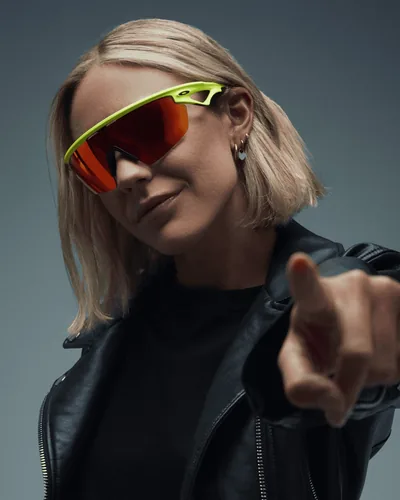 Mujer con lentes deportivos Oakley de mica roja y armazón verde neón