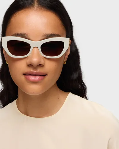 Mujer con lentes de sol TOUS color marfil con detalle dorado