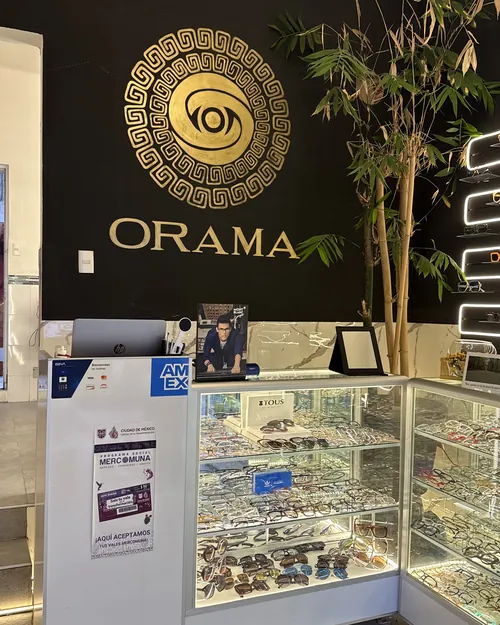 Mostrador de Óptica Órama con vitrinas y el sello dorado en el muro