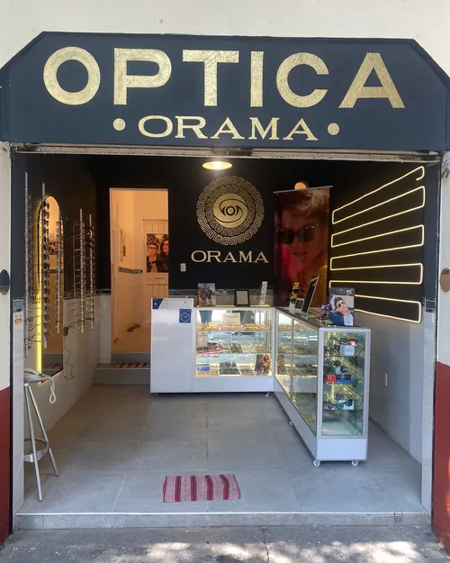 Fachada de Óptica Órama con toldo negro y letras doradas